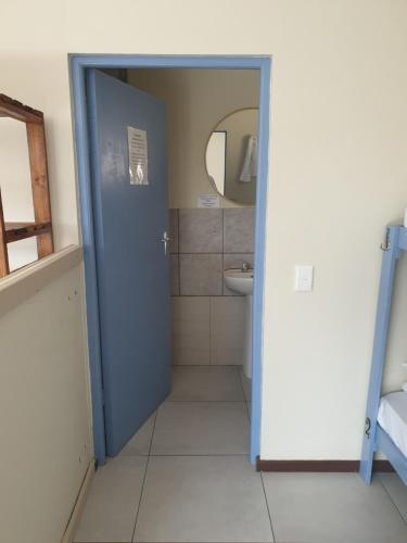 baño con puerta azul y lavamanos en Amakaya Backpackers Travellers Accommodation, en Plettenberg Bay