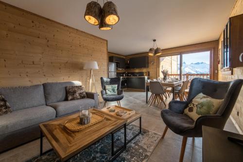 ein Wohnzimmer mit einem Sofa und einem Tisch in der Unterkunft ODYSSEE CRC04 - Charmant appartement sur les pistes in La Toussuire