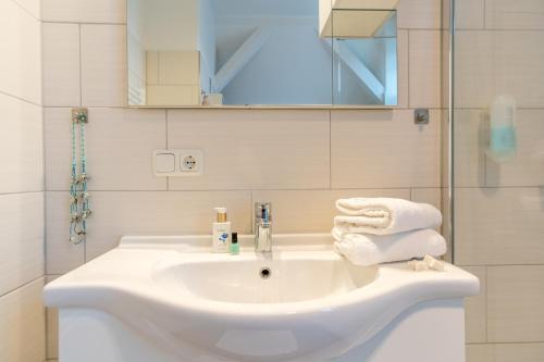 a white bathroom with a sink and a shower at Ein Bett im Norden in Fehmarn