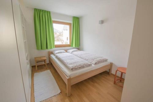 een slaapkamer met een bed met groene gordijnen en een raam bij Ora et labora in Malles Venosta