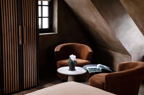 a room with two chairs and a table with flowers at Hôtel Saint-Delis - La Maison du Peintre - Relais & Châteaux in Honfleur