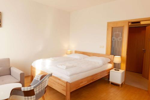 um pequeno quarto com uma cama e uma cadeira em Vitkov Park Apartment em Praga