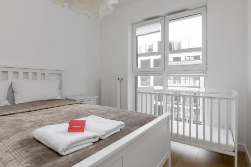 biała sypialnia z łóżkiem z czerwoną książką w obiekcie Rozłogi Sunny Apartment w Warszawie