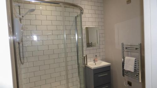 La salle de bains est pourvue de carrelage blanc, d'une douche et d'un lavabo. dans l'établissement Flat 2 Castle Street Serviced Apartments, à Telford
