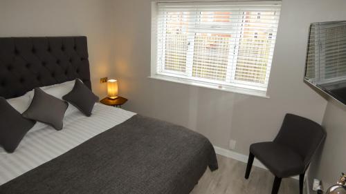 a bedroom with a bed and a chair and a window at Flat 2 Castle Street Serviced Apartments in Telford