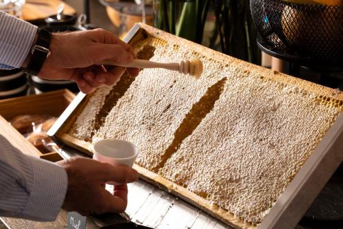 a person is cutting a cake with a utensil at Hôtel Saint-Delis - La Maison du Peintre - Relais & Châteaux in Honfleur