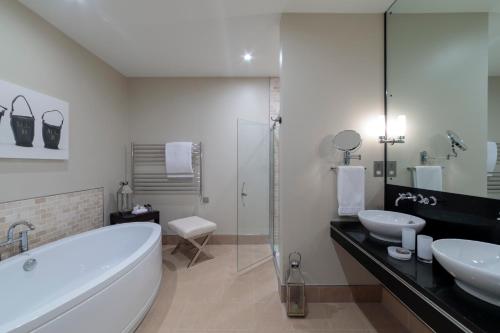 a bathroom with a tub and two sinks and a shower at Bowood Hotel, Spa, and Golf Resort in Chippenham