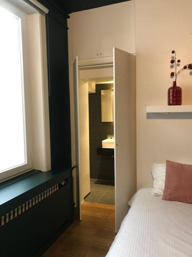 a bedroom with a door open and a white refrigerator at Hotel Goezeput in Bruges