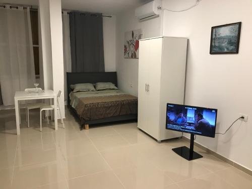 a bedroom with a bed and a flat screen tv at Isramax Apartment near the sea. in Bat Yam