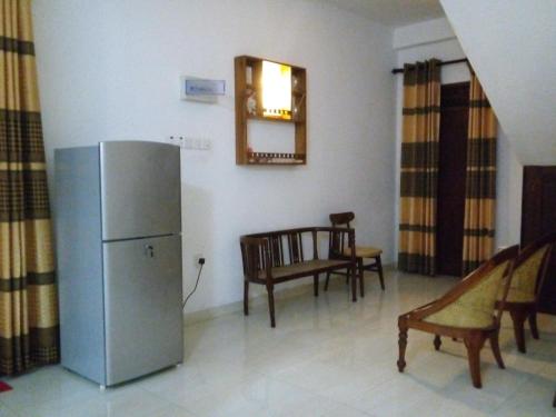 een keuken met een koelkast en een tafel en stoelen bij sinhagiri hotel & restaurant in Tangalle