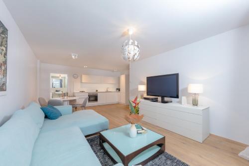 uma sala de estar com um sofá azul e uma televisão em Vienna City Apartments Castelligasse em Viena