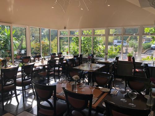 un comedor con mesas, sillas y ventanas en Michelangelos - Rooms, Restaurant & Bar en Gateshead