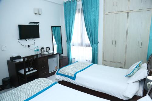 a hotel room with two beds and a television at joerose villa in Noida