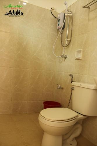 a bathroom with a toilet and a phone on the wall at Alinchlo Hotel in Legazpi