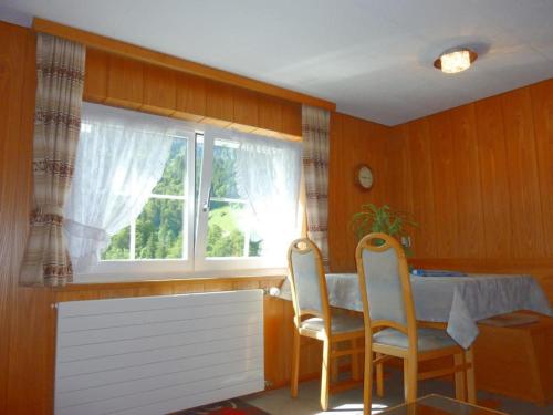 ein Esszimmer mit einem Tisch, Stühlen und einem Fenster in der Unterkunft Apartment Sattelboden 4 by Interhome in Engelberg
