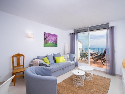 ein Wohnzimmer mit einer blauen Couch und einem Balkon in der Unterkunft Apartment Pueblo Panorama-1 by Interhome in Benitatxell