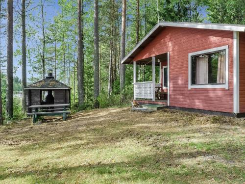 a small red house with a porch and a person in it at Holiday Home Haapalehto by Interhome in Nurmes