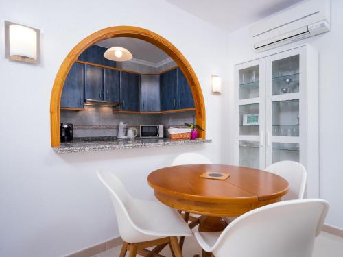 une salle à manger avec une table en bois et des chaises blanches dans l'établissement Apartment Pueblo Panorama-1 by Interhome, à Benitachell