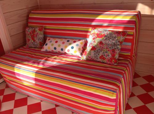 Sofá colorido con almohadas en el suelo a cuadros en la roulotte arc-en-ciel, en Villards-dʼHéria