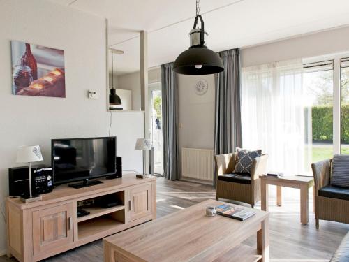 a living room with a television and a table at Holiday Home Bungalowpark It Wiid by Interhome in Eernewoude