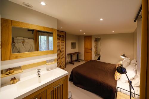 Cottages Domaine du Grand Bec في فيلرفيل: غرفة نوم بسرير ومغسلة ومرآة