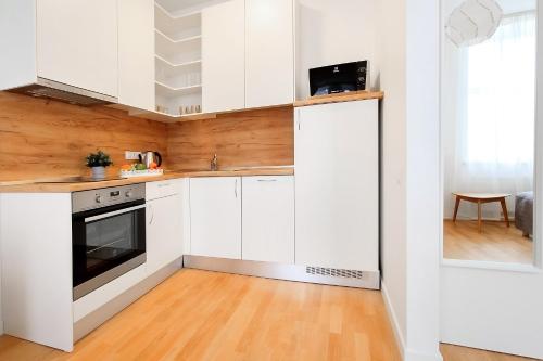 a kitchen with white cabinets and a wooden floor at Residential Barona Apartments in Riga Centre in Rīga