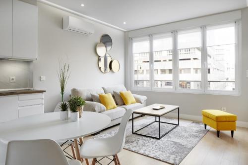 ein weißes Wohnzimmer mit einem Sofa und einem Tisch in der Unterkunft Always Easy I Tabakalera in San Sebastián