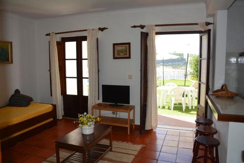 a living room with a bed and a television at Apartamentos Cintra do Vale in Vila Nova de Milfontes