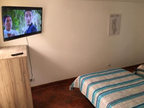 a bedroom with a tv on the wall with a bed at Estadía El Dorado in Bogotá