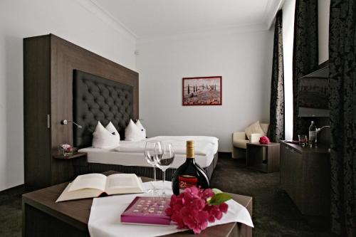 シュターツバート・ブリュッケナウにあるBadhotel Bad Brückenauのベッド、テーブル、ワイン1本が備わる客室です。