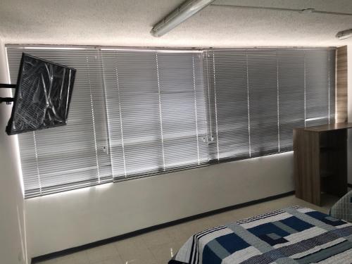 a bedroom with a large window with blinds on it at Estadía El Dorado in Bogotá