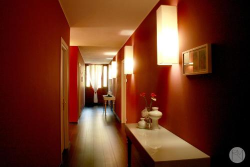 um corredor com paredes vermelhas e uma mesa branca num quarto em Locanda Viridarium em Arqua Petrarca