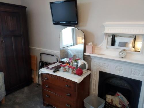 a room with a dresser with a mirror and a fireplace at Anton Guest House Bed and Breakfast in Shrewsbury
