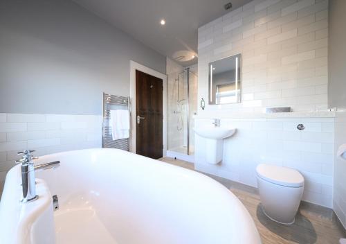 a white bathroom with a tub and a toilet at Miller & Carter Aughton by Innkeeper's Collection in Ormskirk