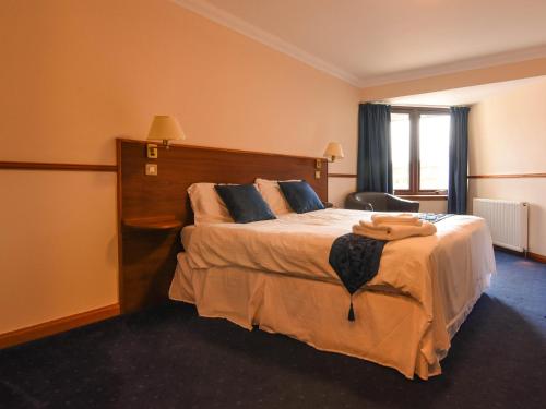 
a hotel room with a bed, desk and a lamp at Findlay's Hotel in Fraserburgh
