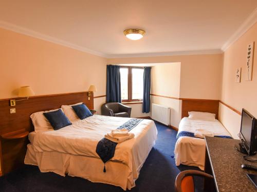 a hotel room with two beds and a desk at Findlay's in Fraserburgh