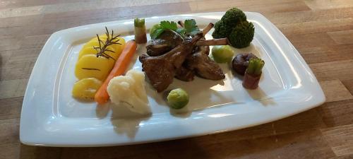 a plate of food with meat and vegetables on a table at Hotel La Cascina in Wennigsen