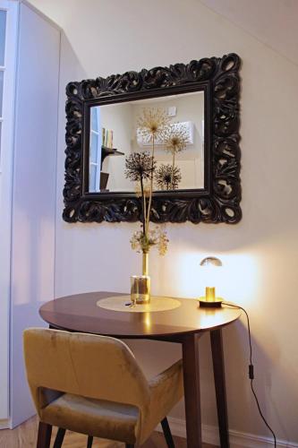 a table with a mirror and a vase with flowers on it at Apartments Satva in Vilnius