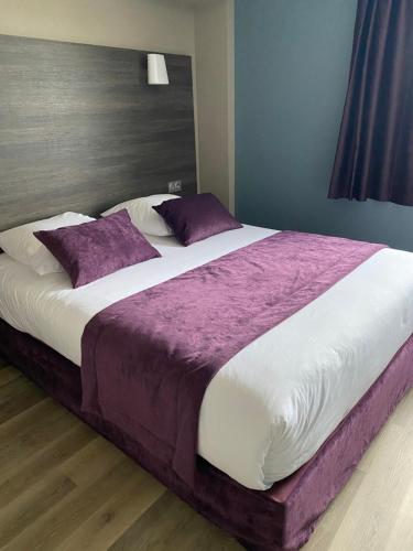 ブザンソンにあるオテル レストラン ヴェゾンティオの大型ベッド(紫と白のシーツ、枕付)