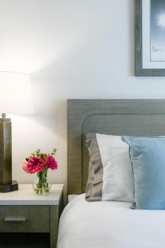 a vase of pink flowers on a night stand next to a bed at Snow King Resort in Jackson