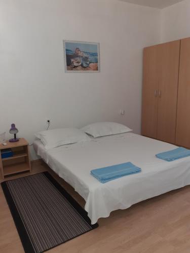 a bedroom with a white bed and a cabinet at Apartman Roko in Novalja