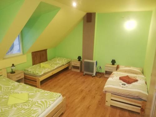 two beds in a room with green walls and wooden floors at privát femamki in Ličartovce