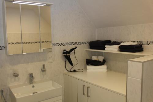 a white bathroom with a sink and a mirror at Ferienhaus am Ruhberg in Winterberg