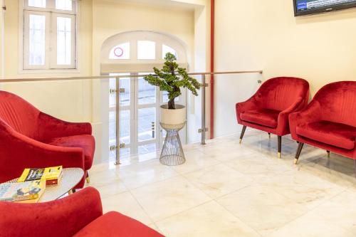 a waiting room with red chairs and a potted plant at Hotel do Norte in Porto