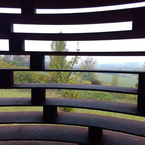 a bench with a view of a field through a window at Hasbania Vakantiewoning in Gingelom