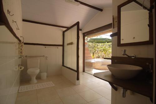 a bathroom with a sink and a toilet and a mirror at Pousada Vale das Araras in Cavalcante