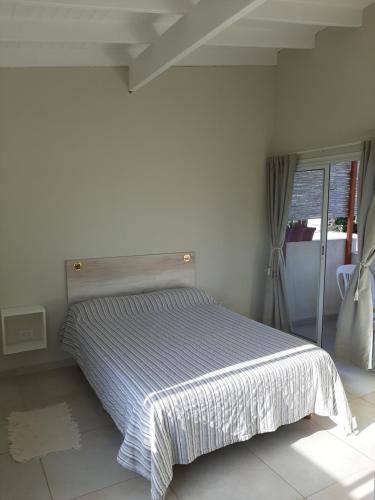 Dormitorio blanco con cama con manta a rayas en Departamentos la Piedad en Mina Clavero