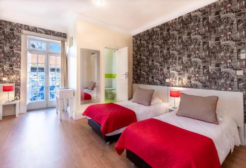 a bedroom with two beds with red sheets at Hotel do Norte in Porto