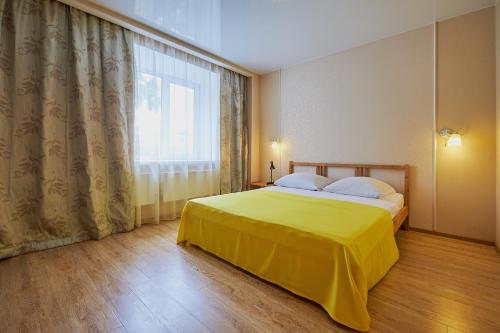 a bedroom with a yellow bed and a window at ОК! Советская, 69 №7 in Tomsk