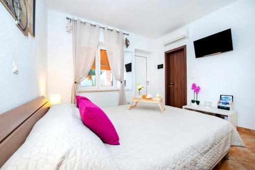 una camera da letto con un grande letto bianco con cuscini rosa di F&R Apartments a Rovigno (Rovinj)